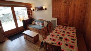 Un accogliente chalet con interni in legno, un tavolo da pranzo con tovaglia fantasia, un divano con cuscini e un frigorifero.