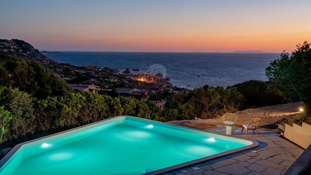 Una piscina con vistas al mar y a un pueblo al atardecer.