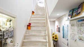 A staircase with a wooden handrail, a potted plant, and a wall with maps and posters. - Apartment Lisbon Castle area and Alfama  (Lisboa)