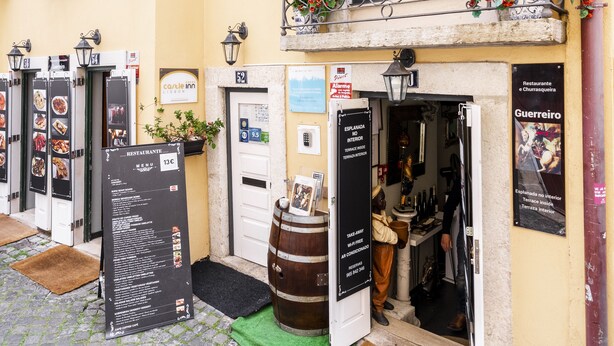 A yellow building with a balcony, a sign for 'Carla Inn', and a menu board outside. - Apartment Lisbon Castle area and Alfama  (Lisboa)