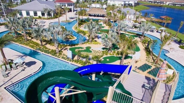 A water park with a large water slide, multiple pools, and palm trees. - Resort acess - Last minute deal (Kissimmee)