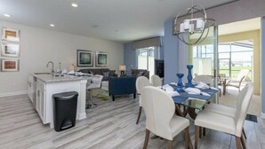 A modern kitchen with a dining area, a sofa, and a view of the outdoors. - Resort acess - Last minute deal (Kissimmee)