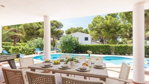 A covered outdoor dining area with a pool in the background. - Villa Gabriel Son Parc by Villa Plus (Son Parc)