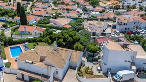 Vista aérea de una zona residencial con edificios blancos, una piscina y una furgoneta estacionada.