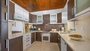 Una cocina moderna con armarios de madera oscura, encimeras blancas, horno empotrado y lavavajillas.