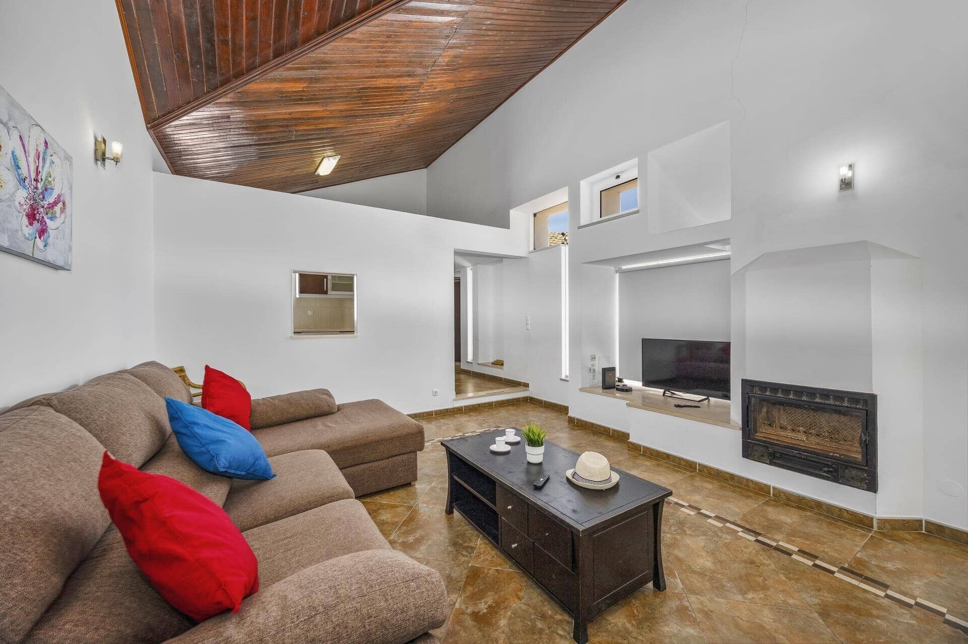 A modern living room with a sectional sofa, a fireplace, and a television.