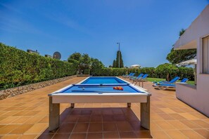 A pool table with blue felt, surrounded by lounge chairs and a clear sky. - Villa Elo by Villa Plus (Albufeira)