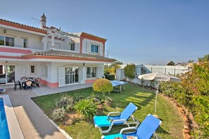 A house with a patio, outdoor seating, a swimming pool, and a garden.
