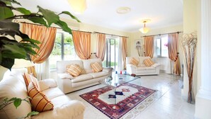A spacious living room with two sofas, a glass coffee table, and a patterned rug. - Villa Rosa by Villa Plus (Olhos de Água)