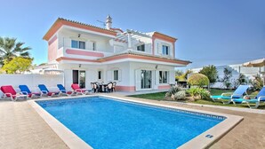 A two-story house with a swimming pool, lounge chairs, and a garden. - Villa Rosa by Villa Plus (Olhos de Água)