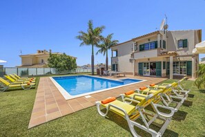 A swimming pool with sun loungers and a barbecue area, surrounded by a well-maintained lawn and palm trees. - Villa Soni by Villa Plus (Olhos de Água)