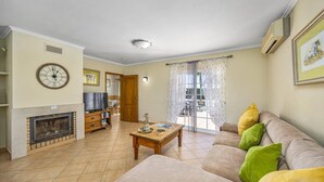A living room with a fireplace, sofa, and a dining area with a table. - Villa Teotel by Villa Plus (Almancil)
