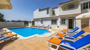 Un bâtiment à deux étages doté d’une piscine, de chaises longues et d’un espace abrité.