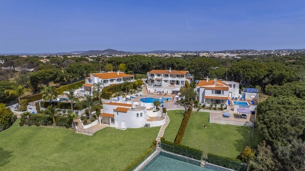 Un vaste complexe de villas modernes comprenant plusieurs bâtiments, une piscine et des jardins bien entretenus.