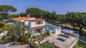 Une maison à deux étages avec une piscine, entourée d’arbres et d’un jardin.