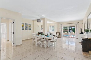 A spacious living area with a dining table, chairs, and a view of a swimming pool.