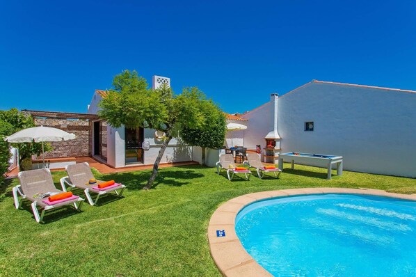 Relax by the serene pool surrounded by a lush lawn and lounge chairs, perfect for outdoor dining and socializing.