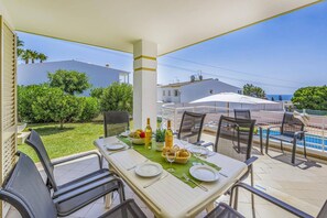 Ein Essbereich mit Tisch für zwei, Gartenstühlen, einem Pool und Meerblick.