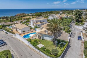 A coastal residential area with a large house featuring a swimming pool, multiple balconies, and a view of the sea. - Villa Primavera by Villa Plus (Albufeira)