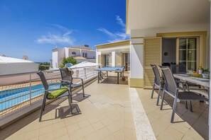 A balcony with a pool, outdoor seating, and a view of the sea. - Villa Primavera by Villa Plus (Albufeira)