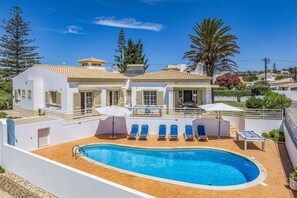 A residential property with a swimming pool, multiple lounge chairs, and a patio area. - Villa Primavera by Villa Plus (Albufeira)