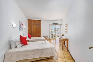 A hotel room with two beds, a desk, and a view of the pool. - Villa Primavera by Villa Plus (Albufeira)