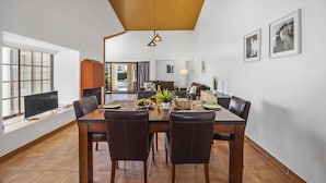 Zona pranzo con tavolo in legno, sedie in pelle e soffitto con trave in legno.