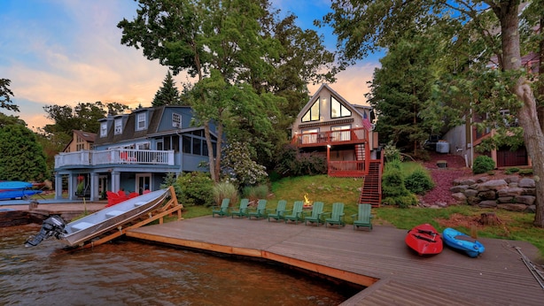 A lakeside property with a dock, kayaks, and a house with a deck.