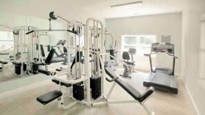 Ein Fitnessstudio mit verschiedenen Trainingsgeräten, Laufbändern und einer Spiegelwand.