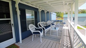 A covered porch with white wicker furniture and a blue exterior wall.
