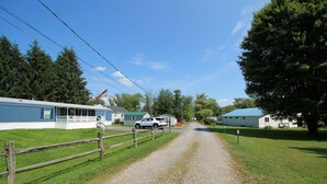 A gravel road leading to a row of mobile homes with a wooden fence on one side.