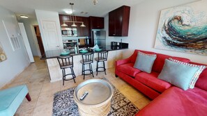 Un espacio habitable pequeño con kitchenette, un sofá rojo y un cuadro en la pared.