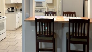 Eine moderne Küche mit weißen Schränken, einem Holztisch und zwei Holzstühlen.