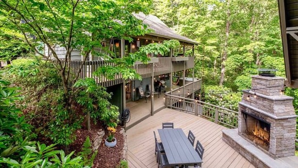 A multi-level wooden deck with outdoor furniture, surrounded by dense greenery. - Amazing Chalet Hot Tub Sauna Fire Pit Pet Friendly (Brevard)