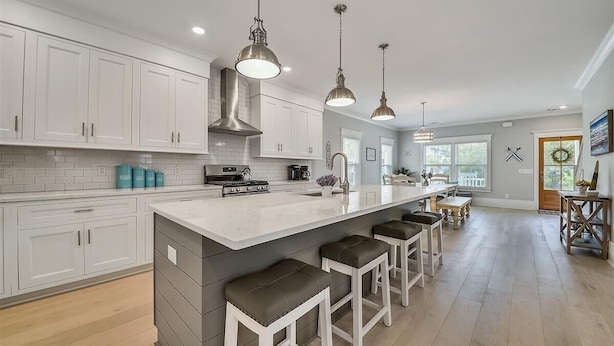 A modern kitchen with white cabinets, a large island with bar stools, stainless steel appliances, and pendant lighting. - 1 Shore Crest, Large Pool, Ping Pong, Beach, Free Golf, Outdoor Kitchen (Hilton Head)