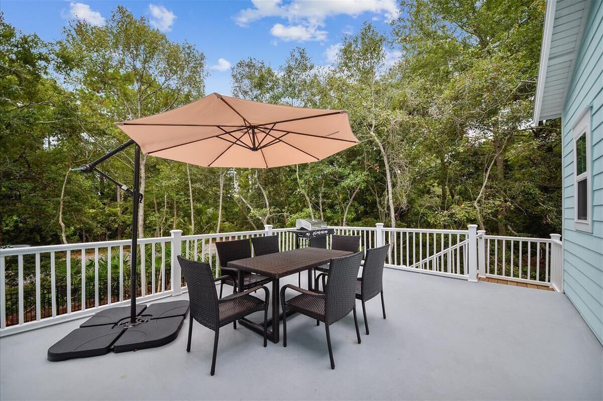 An outdoor patio with a table and chairs, a large umbrella, and a grill.