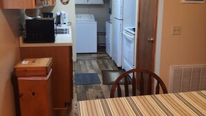 A compact kitchen with wooden cabinets, a microwave, a stove, and a refrigerator.