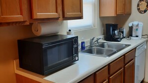A kitchen with wooden cabinets, a microwave, a coffee maker, and a dishwasher.