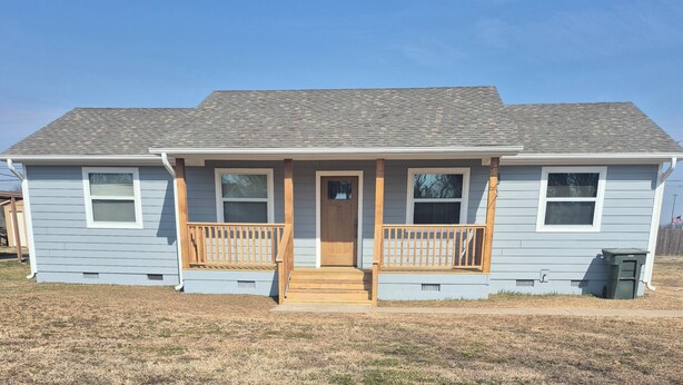 A single-story house with a front porch, a wooden door, and a small front yard.