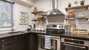 A modern kitchen with dark cabinetry, stainless steel appliances, and decorative items on shelves. - Contemporary Oasis in the Heart of Old Strathcona (Edmonton)