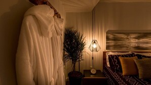 A cozy bedroom with a bed, a nightstand, a potted plant, and a hanging light fixture. - Contemporary Oasis in the Heart of Old Strathcona (Edmonton)