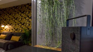 A modern living room with a sofa, a wall with yellow flower patterns, and a hanging plant. - Contemporary Oasis in the Heart of Old Strathcona (Edmonton)