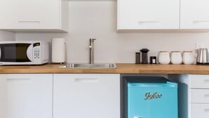 Ett modernt kök med vita skåp, en diskho i rostfritt stål, en mikrovågsugn och en turkos förvaringsenhet med texten ”Igloo”.