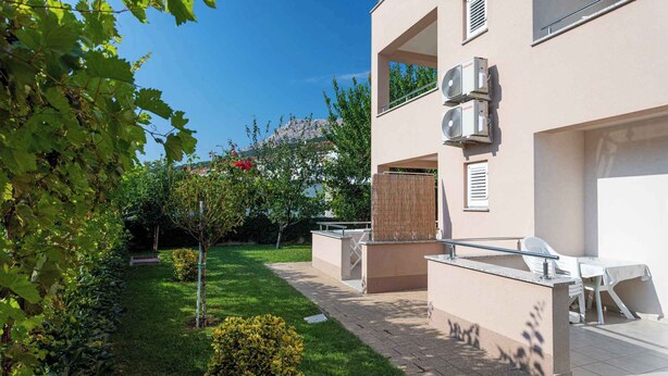 A modern building with outdoor seating, a well-maintained garden, and a clear view of the surrounding landscape. - Holiday apartment 100 m from the sea (Baška)