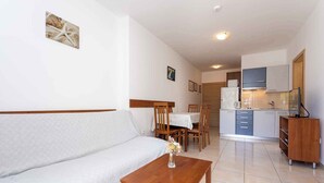 A modern living room with a sofa, a wooden coffee table, and a dining area with chairs and a table. - Holiday apartment 100 m from the sea (Baška)