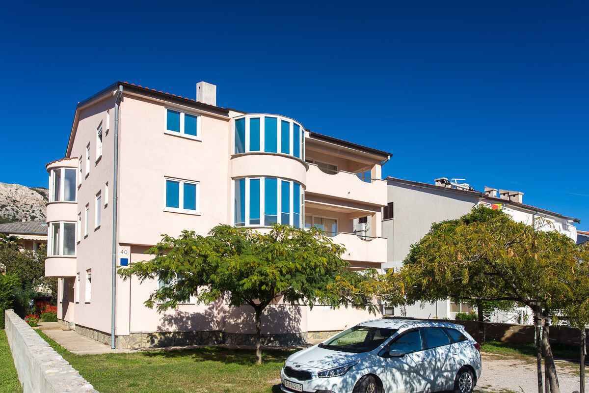 Edifici residencial de diverses plantes amb façana corba, número 40, i un cotxe aparcat al davant.