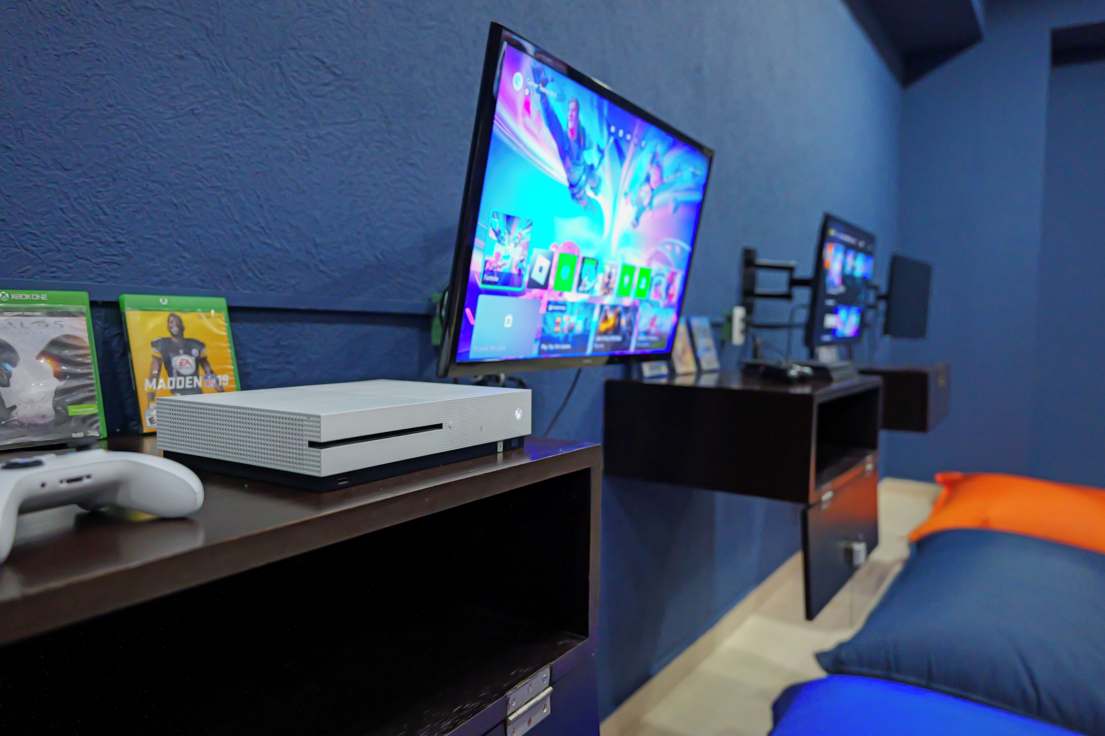 Un equipo de juego con televisor, consola Xbox y juegos sobre un escritorio.