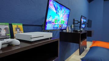 Un equipo de juego con televisor, consola Xbox y juegos sobre un escritorio.