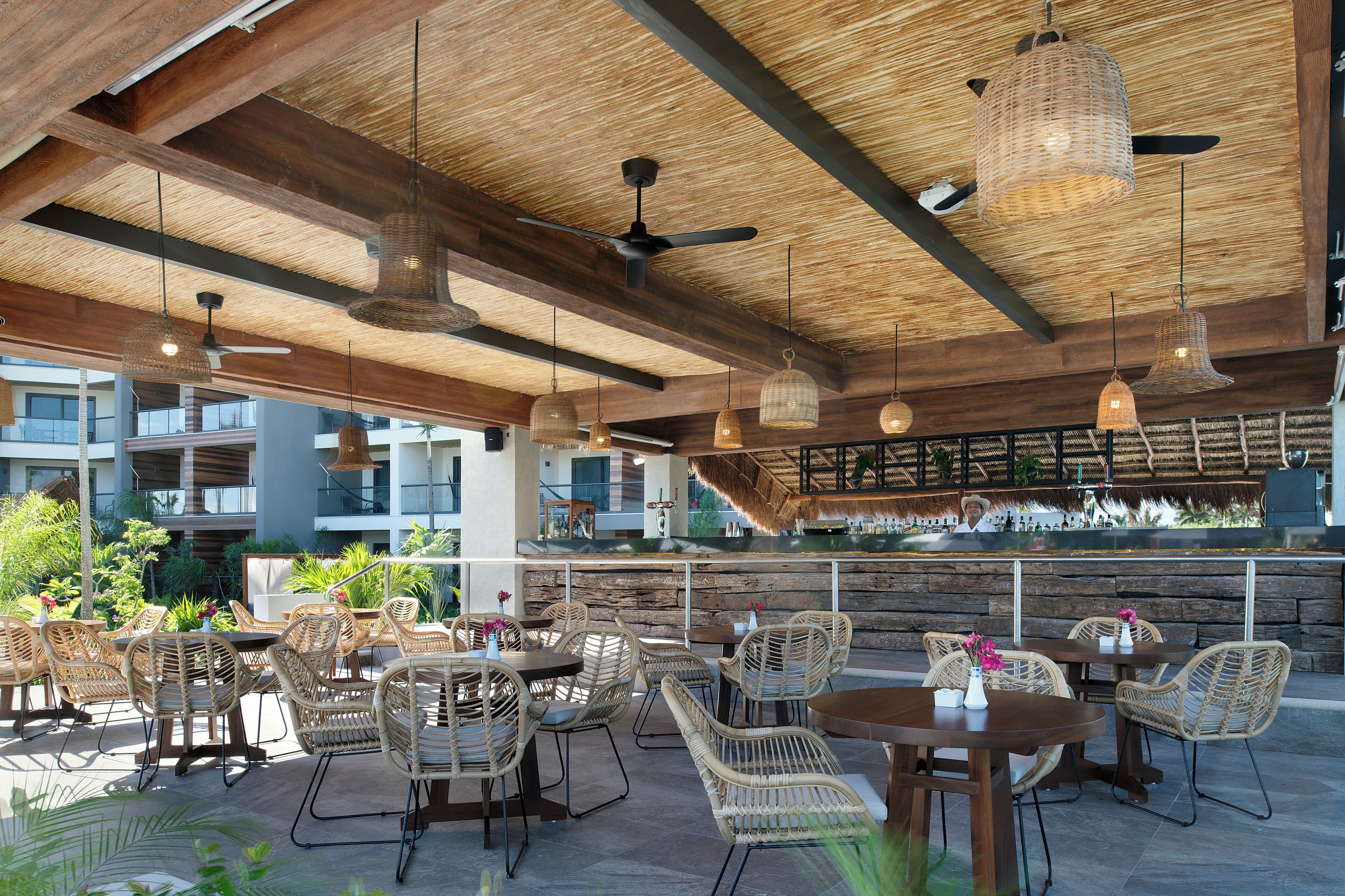 An outdoor dining area with wicker furniture and hanging lights.