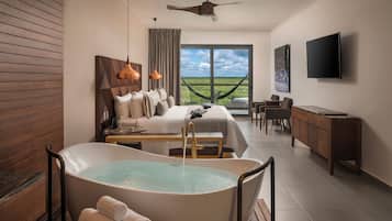 Une chambre d’hôtel moderne dotée d’une grande baignoire, d’un lit avec vue, d’un bureau et d’une télévision.